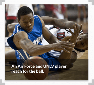 A photo showing an Air Force and UNLV player both reach for a ball during a basketball game