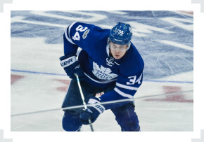 Auston Matthews skating two hand on stick Leafs jersey