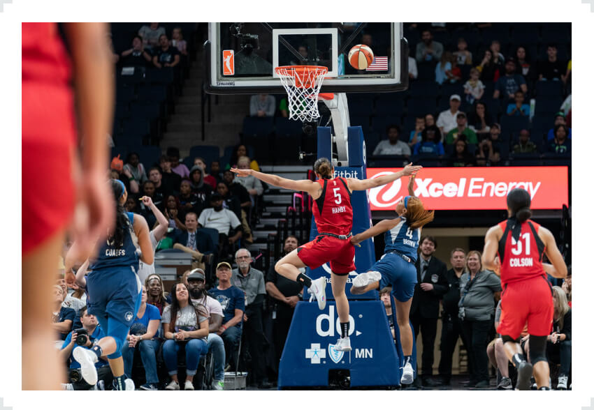 WNBA players jumping through air towards basket