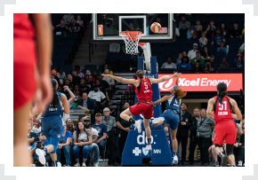 WNBA players jumping through air towards basket