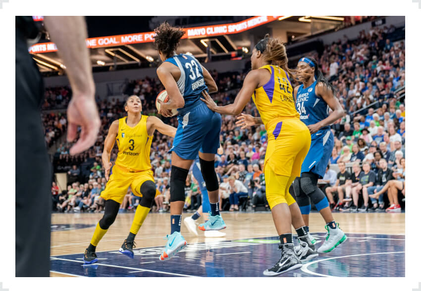 WNBA player with ball in hands defended by opponent