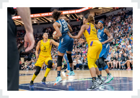WNBA player with ball in hands defended by opponent