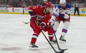 Carolina Hurricanes center Sebastian Aho skates with puck past New York Rangers defenseman Ben Harpur